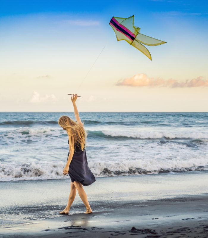 A,Young,Woman,Launches,A,Kite,On,The,Beach.,Dream,