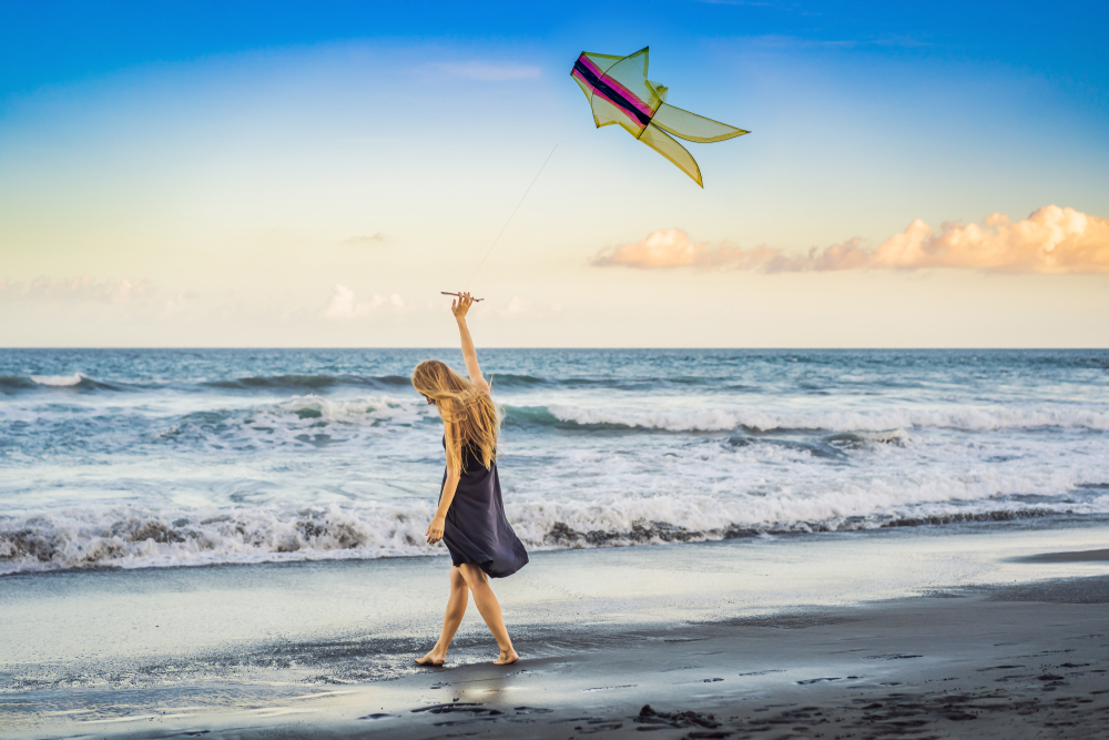 A,Young,Woman,Launches,A,Kite,On,The,Beach.,Dream,