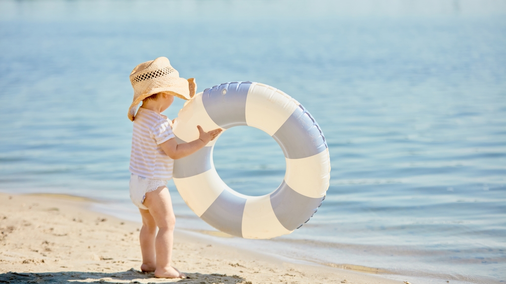Toddler,In,Straw,Hat,With,Inflatable,Swim,Ring,Near,Water.